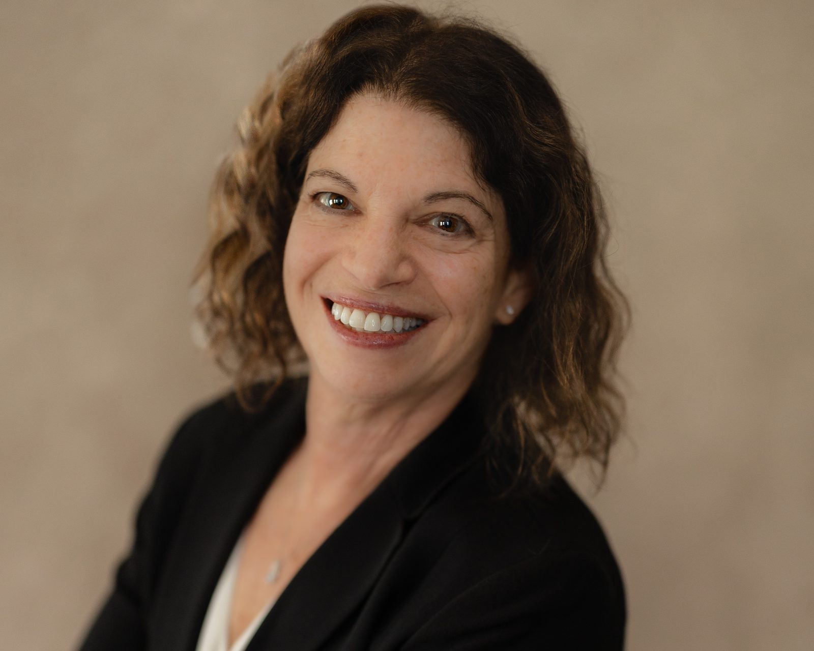 Executive headshot, warm neutral backdrop