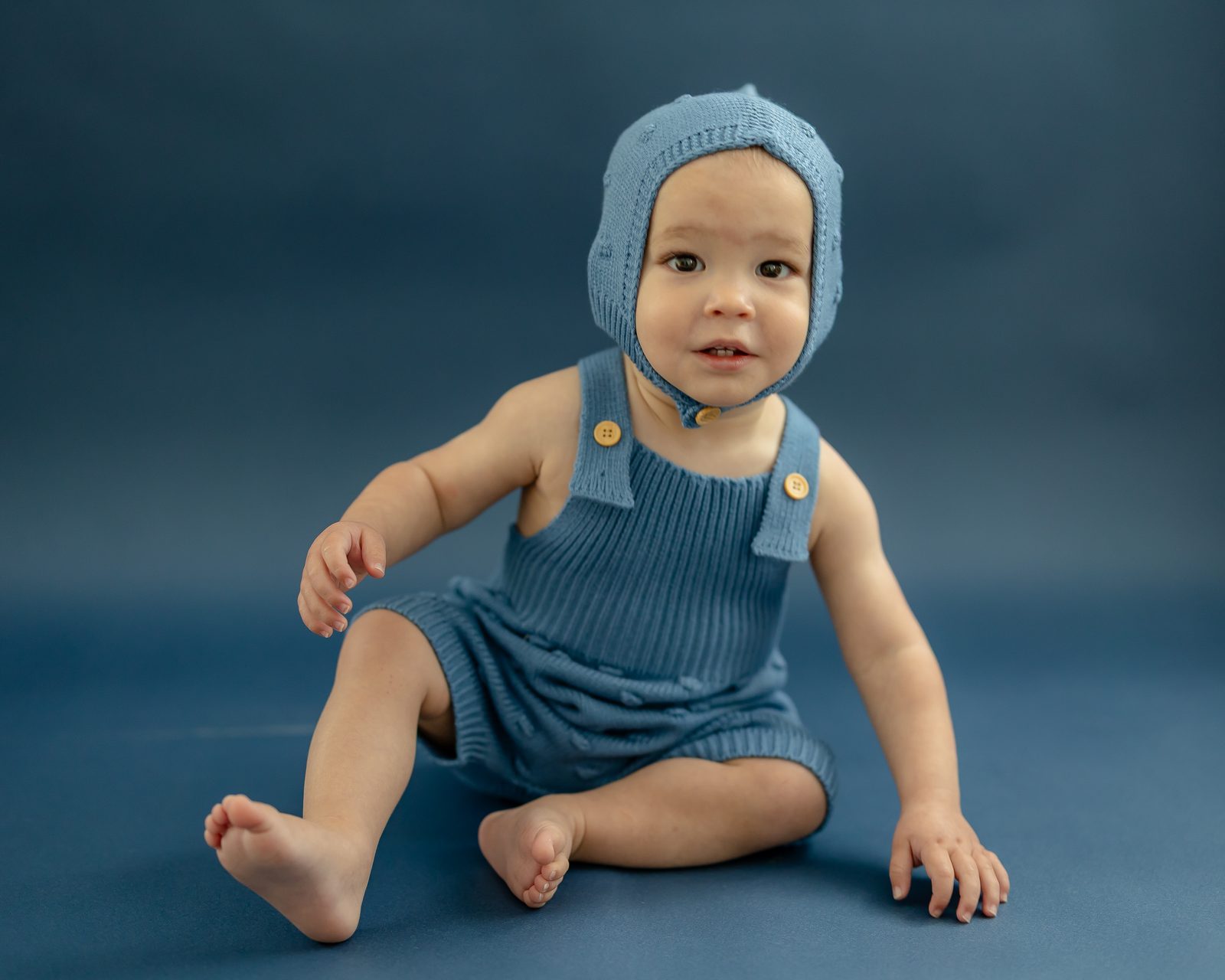 Baby in blue knit bonnet and overalls